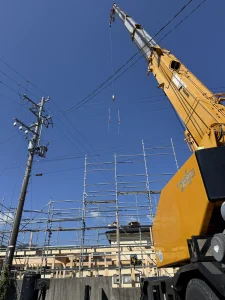茅野市の建て方現場で架空線近くに旋回する16tクレーンのブーム